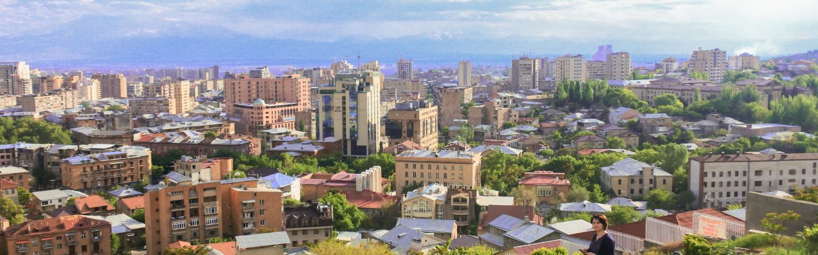 The city of Yerevan with mountains covered in fog in the distance. 